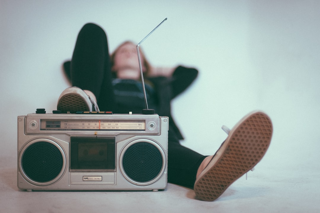 A person in sneakers resting feet on a vintage silver boombox