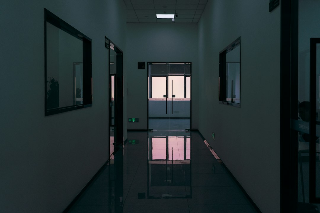 Dark, modern hallway with reflective floor and windows