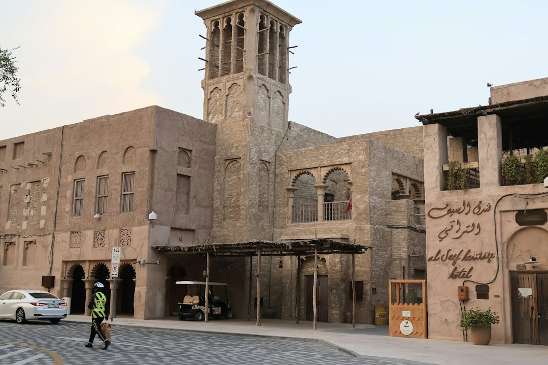 A person in a high-visibility vest walking past the Al Seef Heritage Hotel