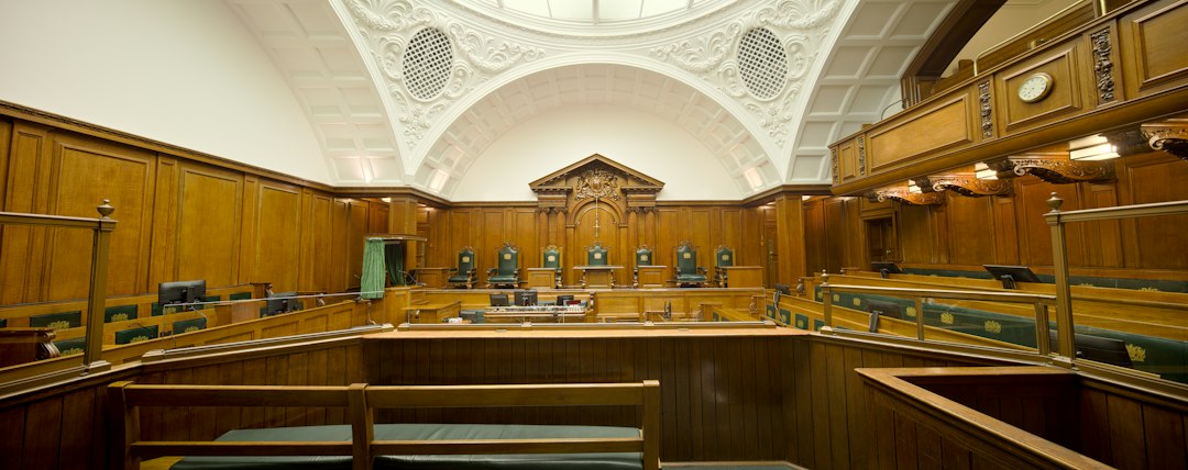Empty courtroom featuring rich wooden paneling and a decorative ceiling