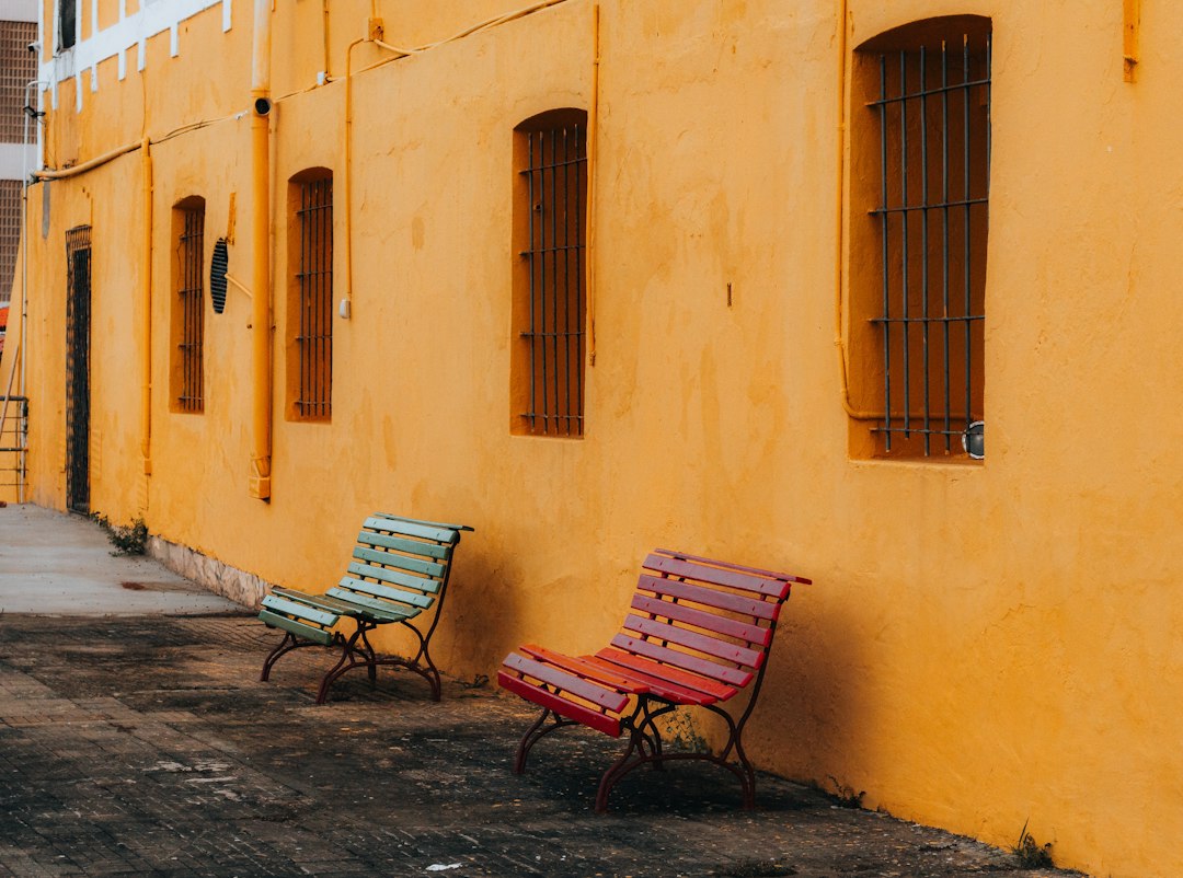 Two colorful benches against a yellow wall