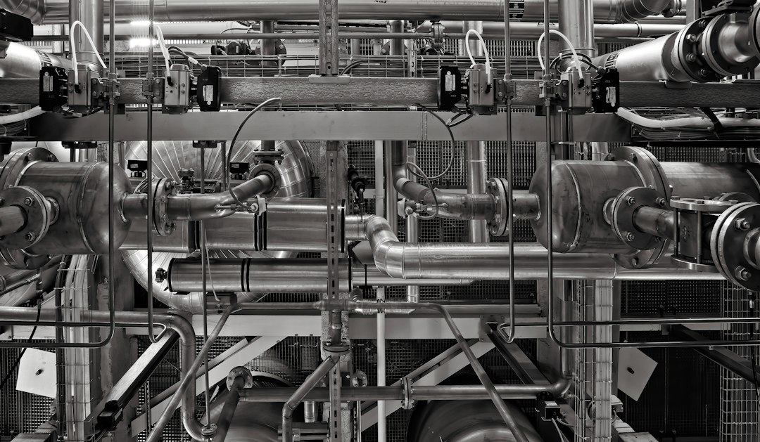 A complex network of industrial metal pipes and valves in a factory setting