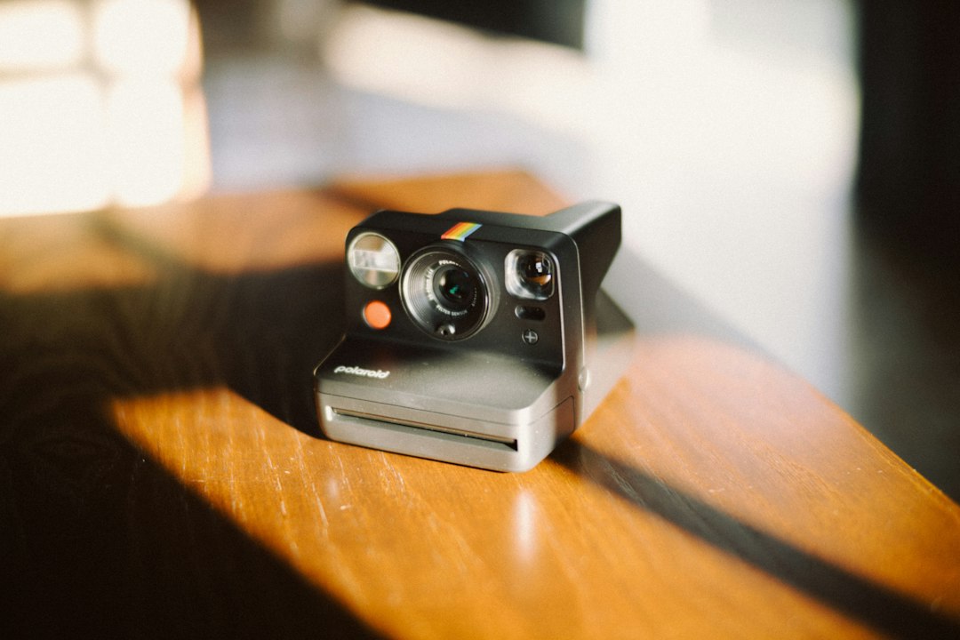 A vintage instant camera sits on a wooden table