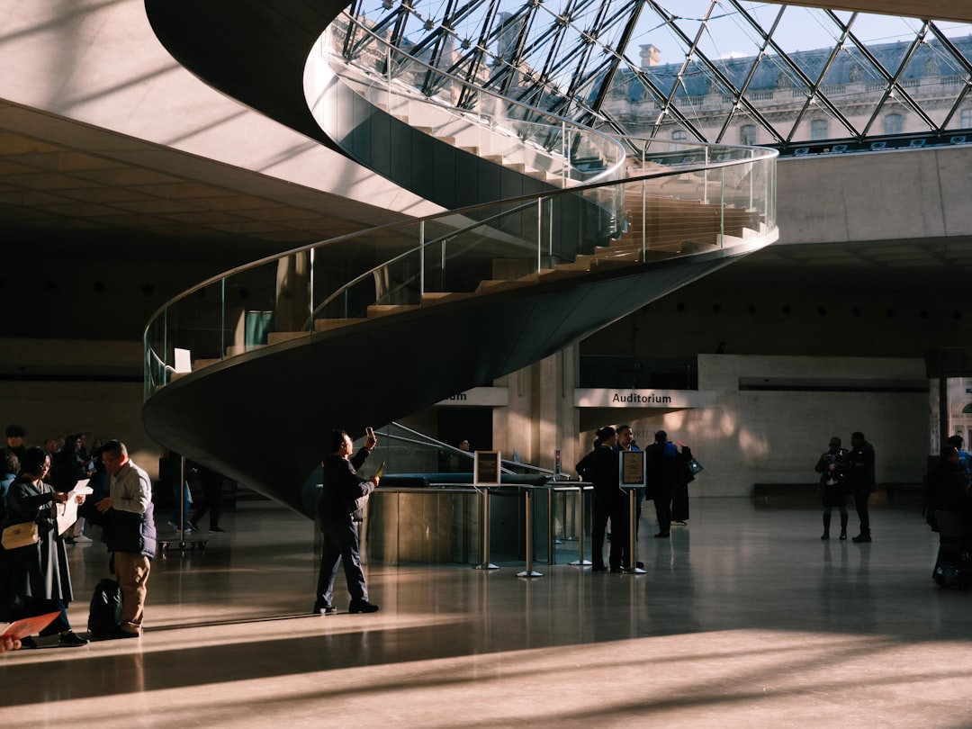 Modern spiral staircase in a sunlit atrium with people