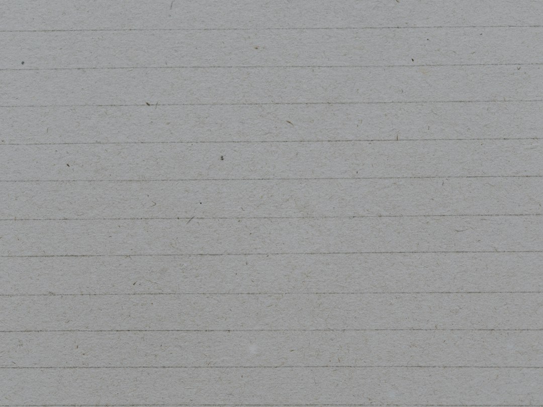 a black and white cat sitting on a piece of lined paper