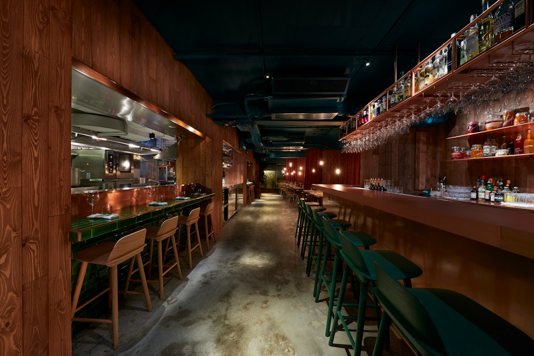 Modern bar interior with wooden accents and green stools