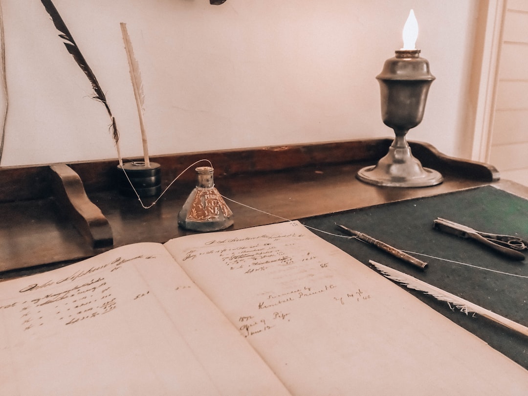 Scrivania d'epoca con libro aperto, calamaio e lampada accesa